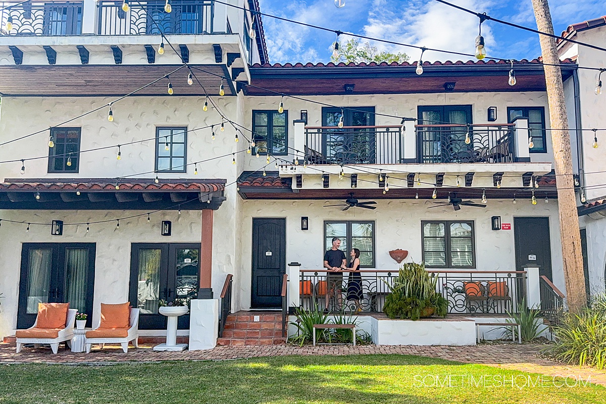 Side of the Black Dolphin Inn, a boutique hotel in New Smyrna Beach with a couple in front of a window on the elevated walkway area on the side of the building.