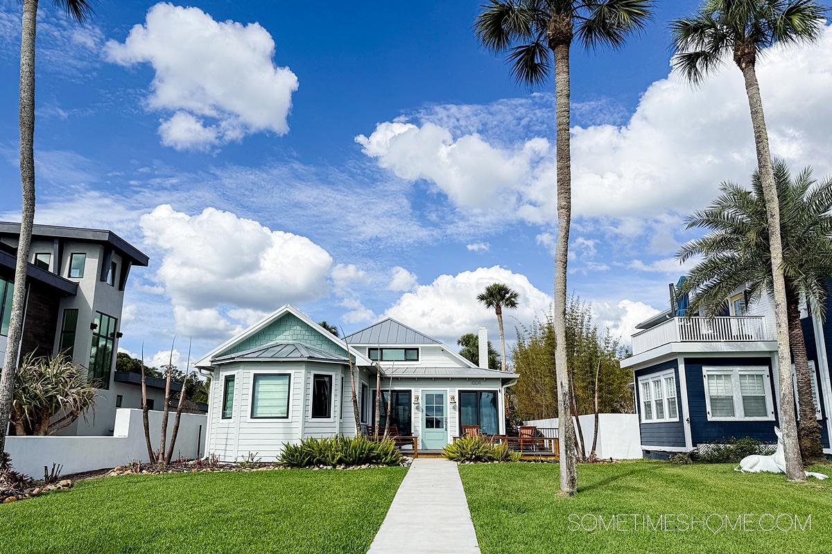Charming house set back from the sidewalk with an expansive green lawn leading up to it and a single palm tree.