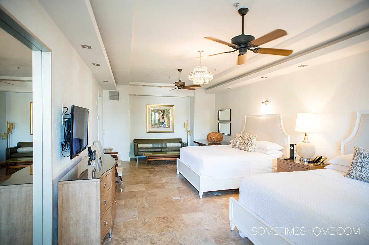 hotel room with two beds and an overhead fan with white walls