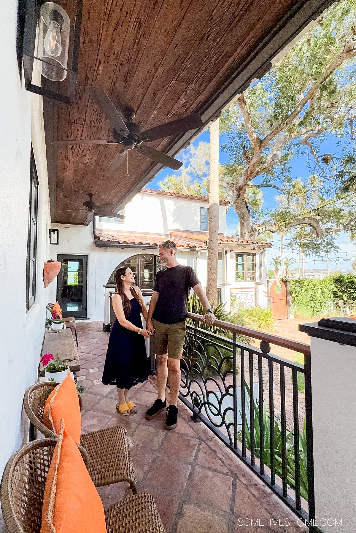 Couple on the walkway of a boutique hotel leaning against a railing.