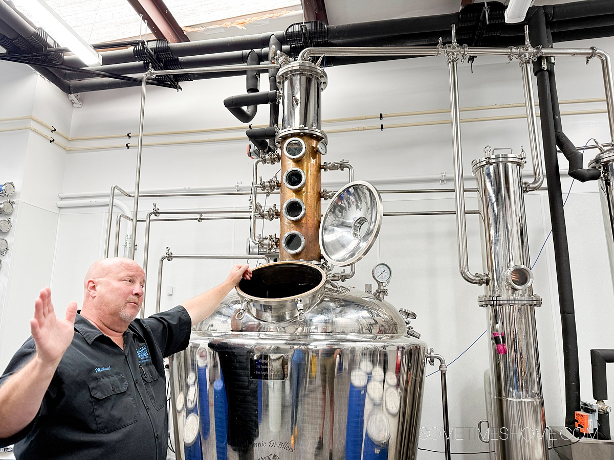 Man showcasing the distillery process with a still next to him at Sugar Works Distillery in New Smyrna Beach.